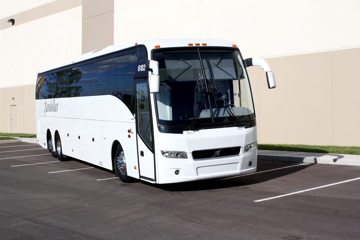White Sandollar full-size motorcoach with the company script on its side, front three-quarter view
