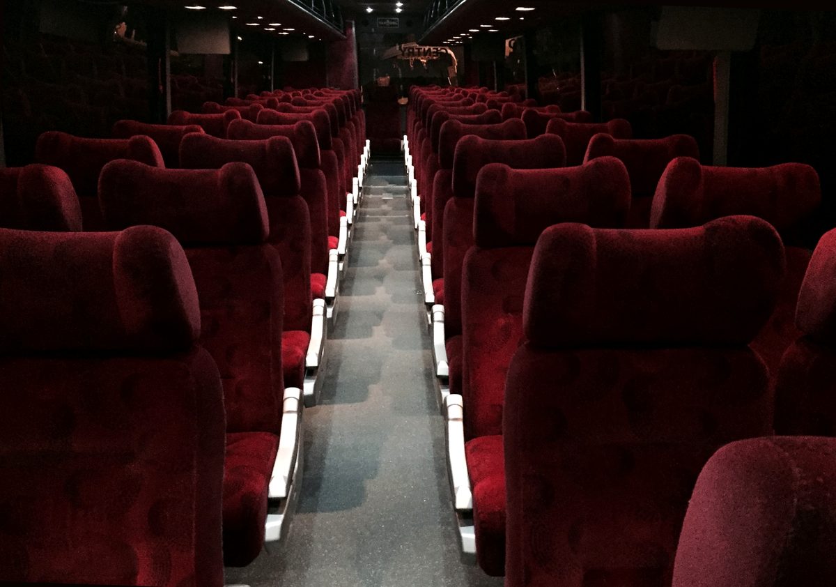 Full-size motorcoach cabin with burgundy upholstered seats along a center aisle